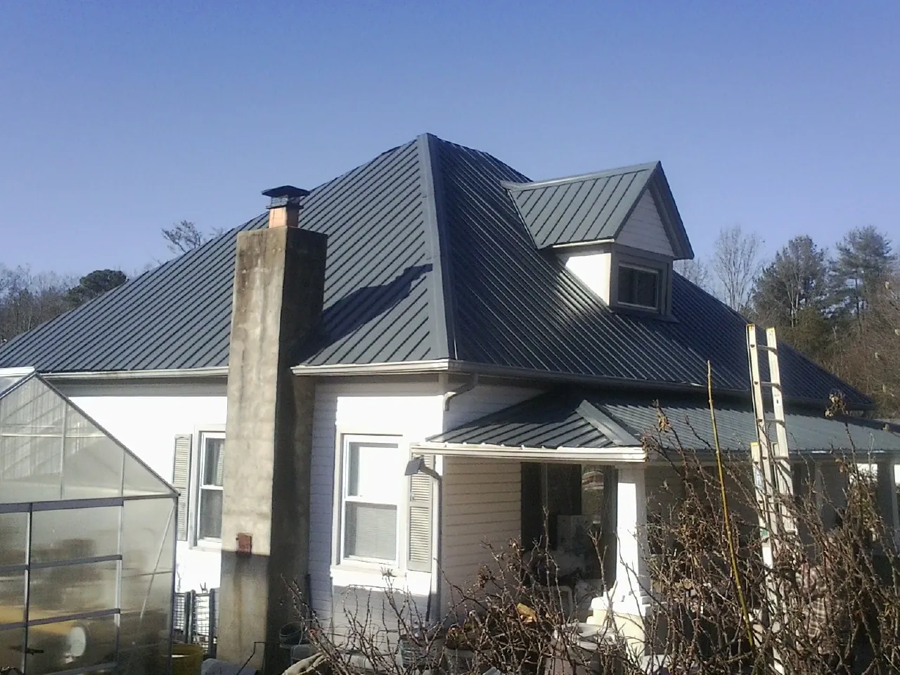 Dark blue standing seam metal roof on a white farmhouse with dormer — Slate & Tile Roof Repair by Roofing Brothers in Stevensville