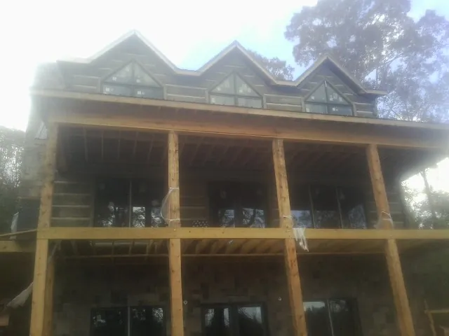 Dormers and porch framing on a large log home under construction — Roof Coating work by our crew in Stevensville