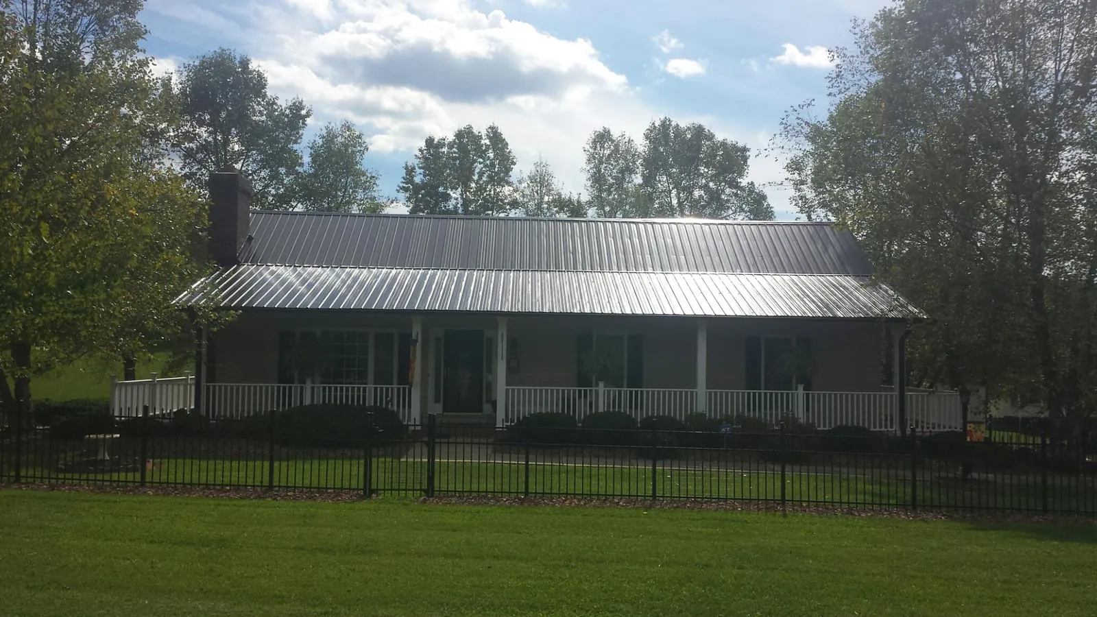Gray metal roof on a brick ranch with a full width front porch — Gutter Guard Installation work by our crew in Stevensville