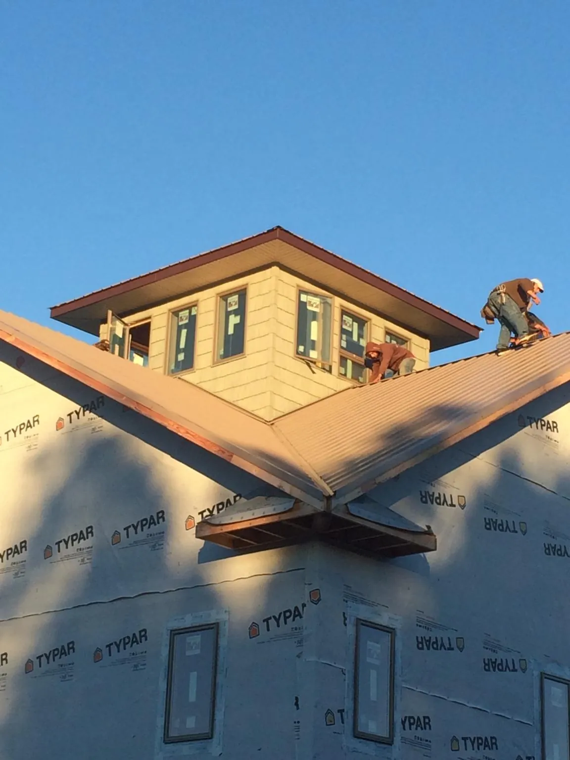 Roofers working around a rooftop cupola on a new metal roof at sunset — Roof Waterproofing in Stevensville by Roofing Brothers